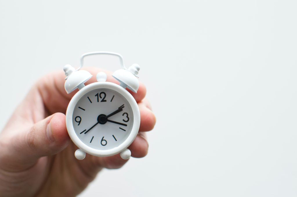 Hand holding small clock.