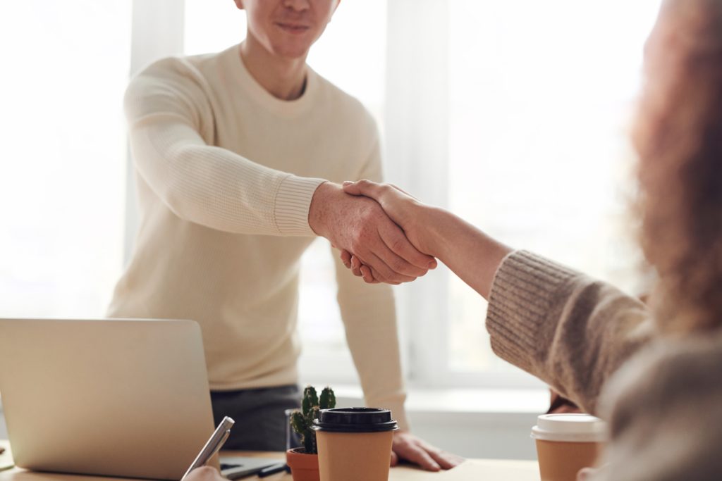 Man shaking a woman's hand across a desk